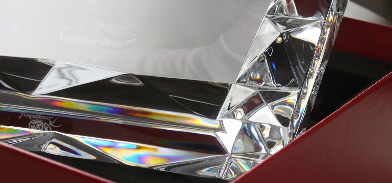 バカラの『ルクソール』フォトフレームを横置きにし、その特徴であるピラミッド状のダイナミックなカッティングを間近で捉えたアップ写真。精緻に磨き上げられたクリスタルのエッジが光を鋭く反射・屈折させ、幾何学的な陰影と宝石のような煌めきが連なる、最高級クリスタルならではの造形美と透明感を強調したイメージ。