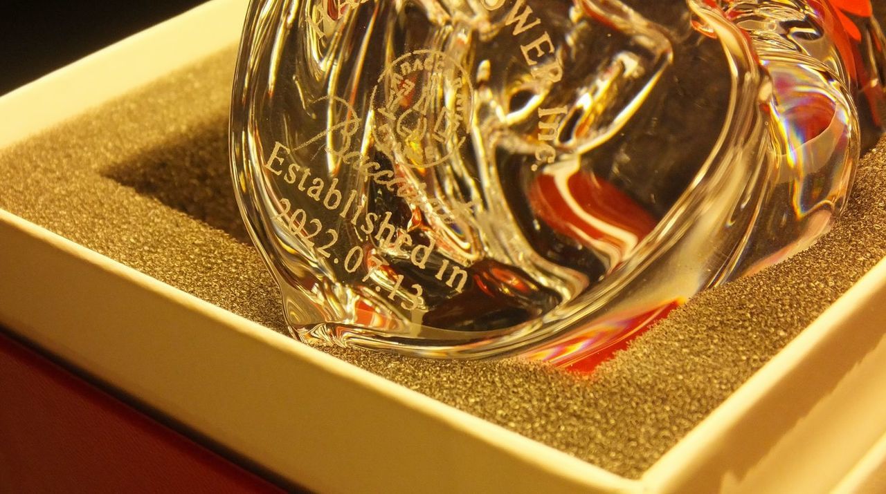 バカラのクリスタル製置き時計『ラランドクロック』の上部に名入れ彫刻を施した退官記念品のサンプル画像。天文学者ラランドの名を冠した円形の星のようなデザインのクリスタル上部に、『退官記念 腎G一同 令和3年』という文字が精巧に刻印されている。透明度の高いクリスタルが周囲の光を反射し、長年の医療・研究への貢献を称えるメッセージを格調高く引き立てており、組織の絆と敬意を伝える特別な贈り物であることを表現している。