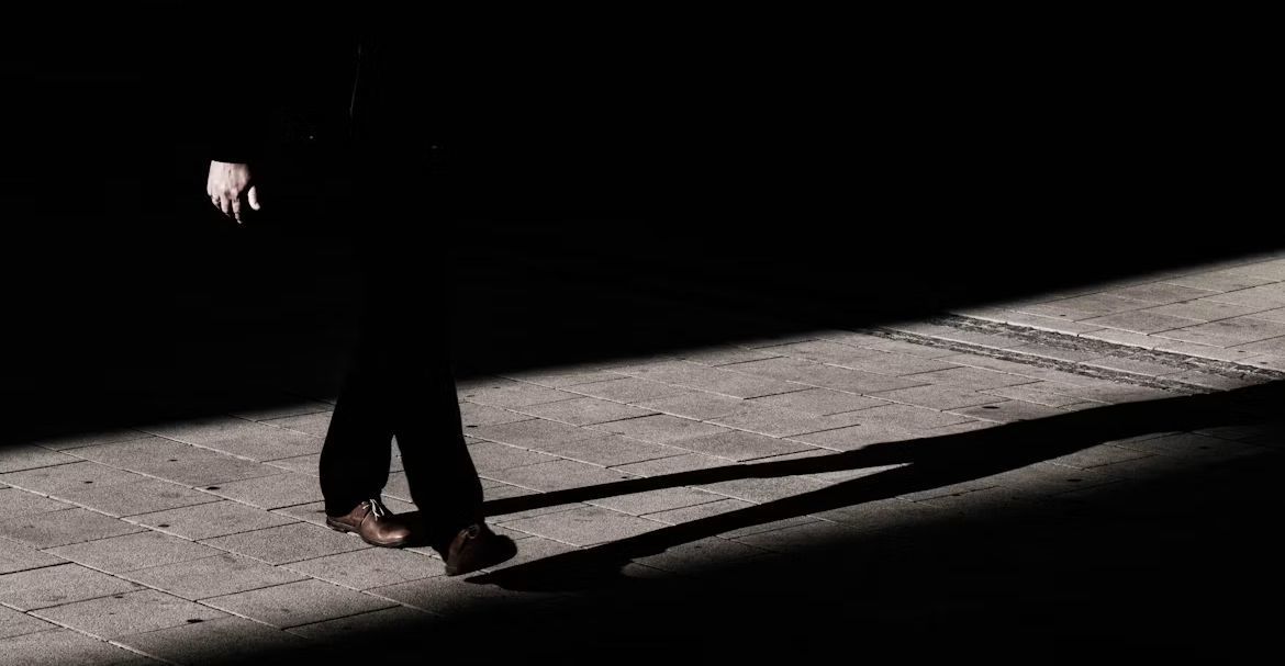 スーツ姿の人物が歩く姿と伸びる影