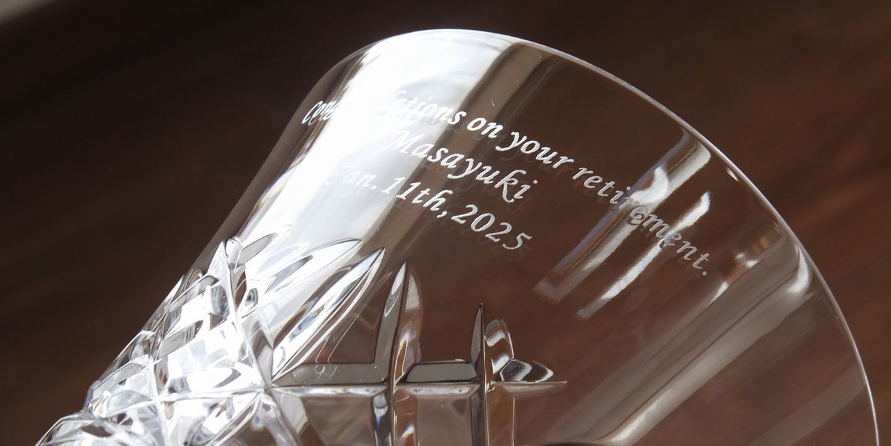 バカラ（Baccarat）の『アリア』タンブラーの側面に、退職祝いのメッセージ『Congratulations on your retirement』、お名前、および日付が精緻に名入れ彫刻された写真。最高級クリスタルガラスならではの美しい透明感と繊細なカットワークに名入れが映え、長年の勤続や功績を称える退職記念、定年退職の祝いなど、感謝と敬意を伝える特別なパーソナライズドギフトにふさわしい格調高いイメージ。