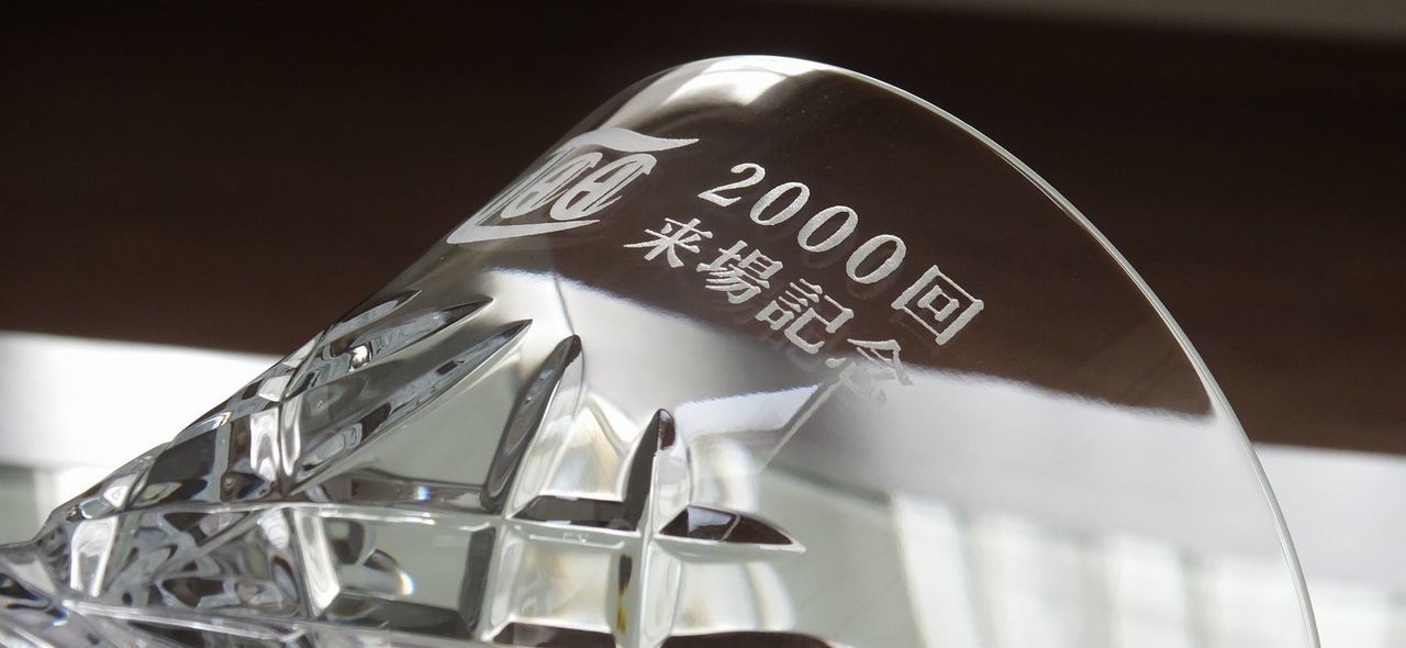 バカラのアリアタンブラー2025の側面に、『2000回来場記念』の文字とロゴデザインが名入れ彫刻した写真。透明なクリスタルに、長年のご愛顧を感謝するメッセージと記念のロゴが繊細に刻まれ、特別な顧客への感謝の気持ちと永続的な関係を表す、価値ある記念品です。