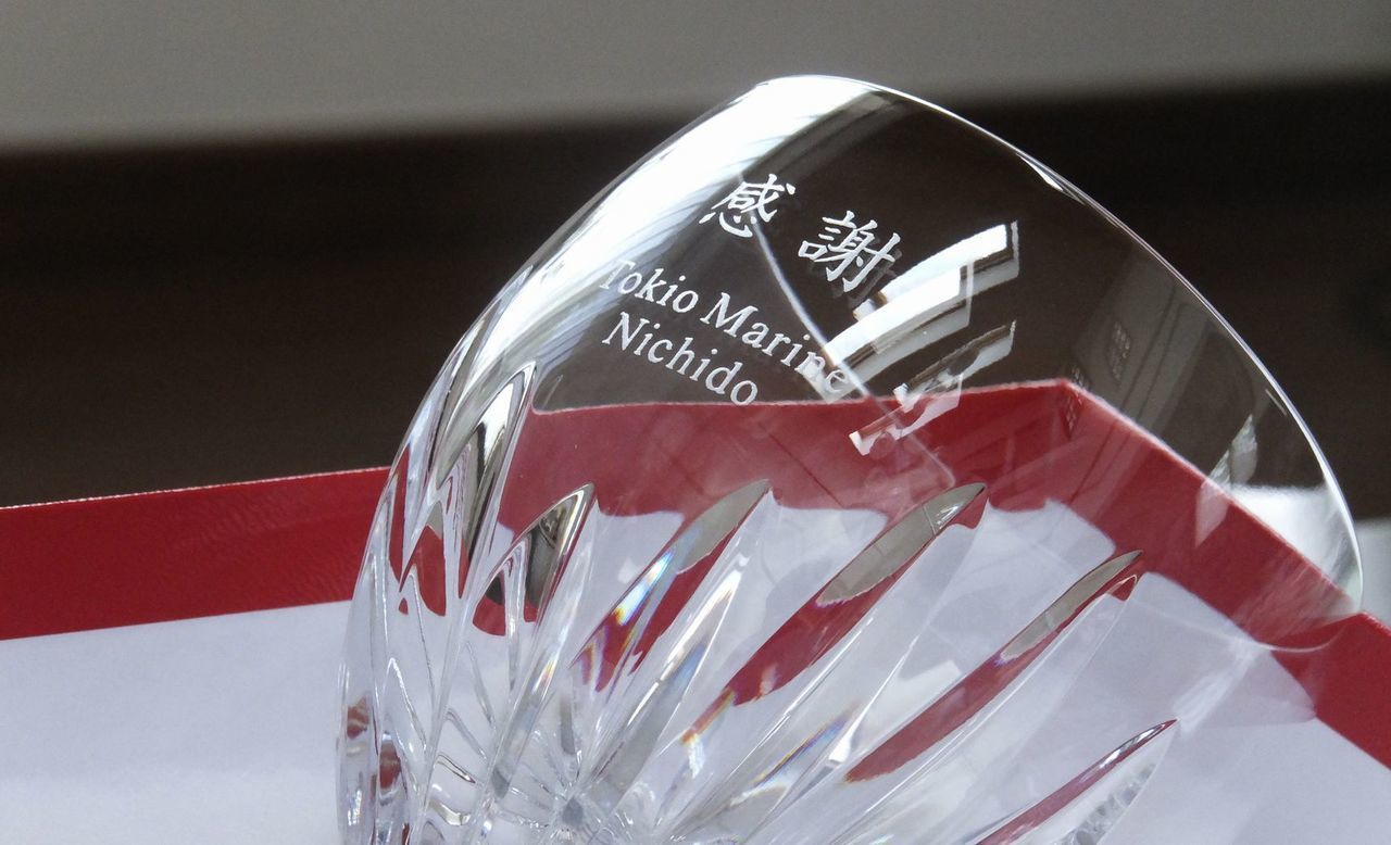 バカラの『マッセナ ワイングラス』の側面に名入れ彫刻を施した退職祝い記念品の制作実績。ナポレオンの元帥の名を冠し、放射状のカットが施された優雅なグラスの側面に、メッセージ『感謝 Tokio Marine Nichido』が英字セリフ体で精巧に刻印されている。格式高いワイングラスに、長年の貢献に対する感謝の念と企業名を刻むことで、重厚な品格と特別な敬意を伝えるハイクラスな記念ギフトとして視覚的に伝えている。