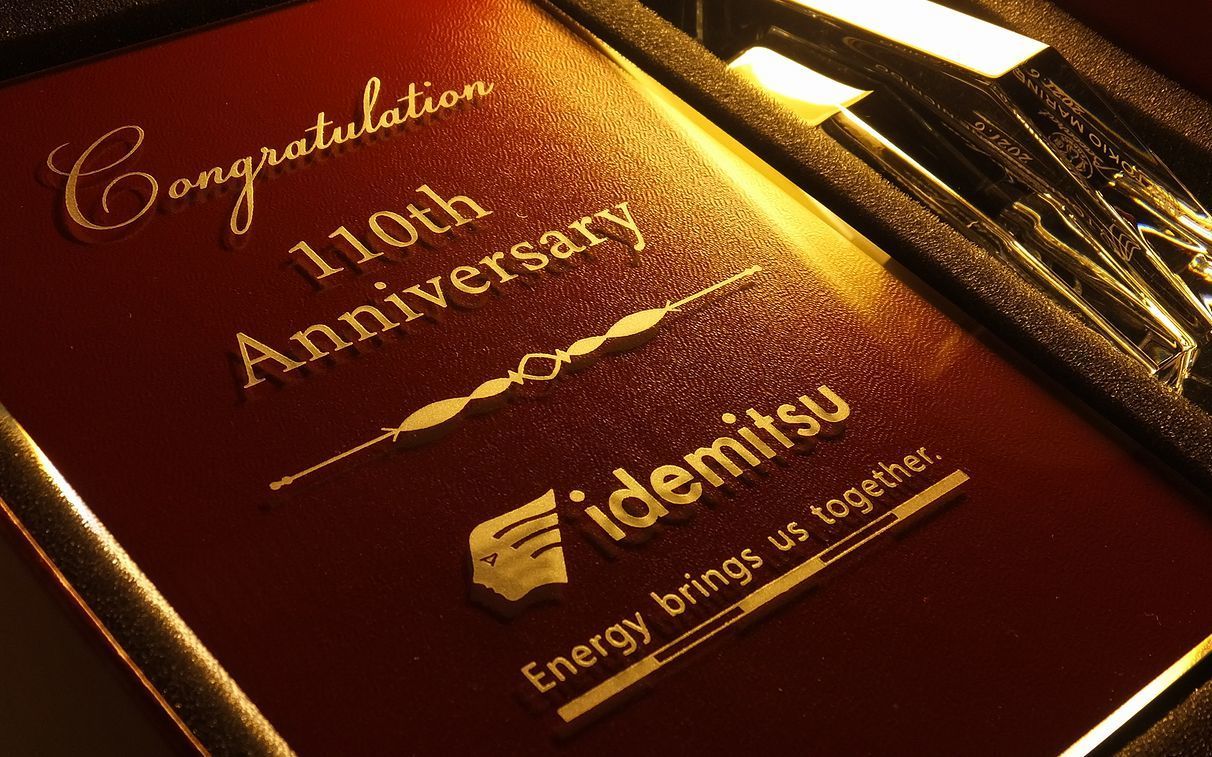 バカラ（Baccarat）のクリスタル製『アビス フォトフレーム』に、出光（Idemitsu）の企業ロゴと『110th Anniversary Congratulations』の文字が精緻に名入れ彫刻された写真。最高級クリスタルならではの深いカットと重厚な透明感に、110周年という偉大な歴史と節目をたたえる刻印が美しく施され、企業の発展と功績を祝う最高峰の周年記念ギフト・法人表彰記念品にふさわしい格調高いイメージ。