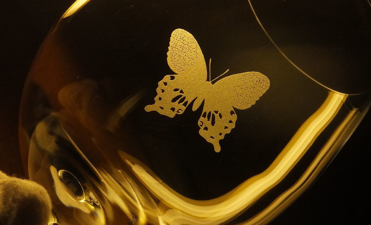 バカラの『デギュスタシオン ボルドー ワイングラス』の側面に名入れ彫刻を施した教授の退職祝い記念品の制作実績。ワインの芳醇な香りを引き出すために設計された大きなボウルを持つグラス側面に、長年研究されてきた蝶のシルエットが繊細かつ優雅に刻印されている。さらに、感謝のメッセージや教授の氏名が添えられている。格式高いワイングラスに、退職される教授の専門分野を象徴するパーソナルなモチーフを刻むことで、深い敬意と、長年の功績を称える極めて特別で心温まる記念ギフトとして視覚的に伝えている。