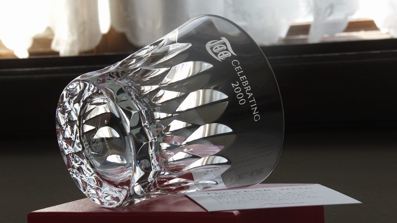 バカラ（Baccarat）の『ダリア タンブラー 2026』の側面に、ゴルフ場のロゴマークと『CELEBRATING 2000』の記念メッセージが精緻に名入れ彫刻された写真。花びらのように華やかなカットワークと2026年の年号が刻まれた最高級クリスタルグラスに、ゴルフコースの伝統やプレステージを感じさせる刻印が美しく映え、ホールインワン記念やクラブの節目、ゴルフコンペの特別賞品など最高峰の法人・スポーツギフトにふさわしい格調高いイメージ。