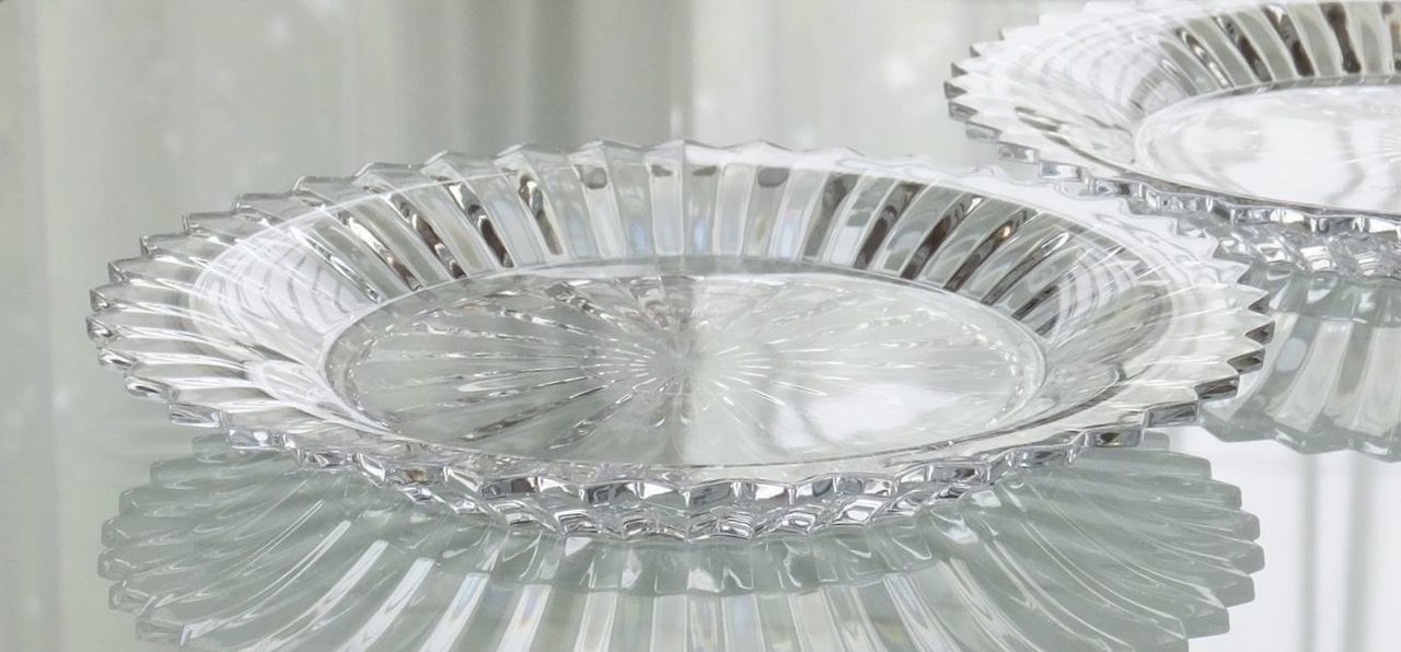 バカラの『ラランド クロック（置き時計）』が、ガラスのテーブルの上に4つ横一列に並べられている様子の写真。ドーム型の重厚なクリスタルと、クラシカルな時計の文字盤を持つクロックが、同じ間隔で整然と配置されている。連続して並ぶクリスタルの輝きは、企業や団体への大口の記念品、または役員への特別ギフトとしての重厚感と高い格式を強調し、時の流れと継続的な成功を象徴的に表現している。