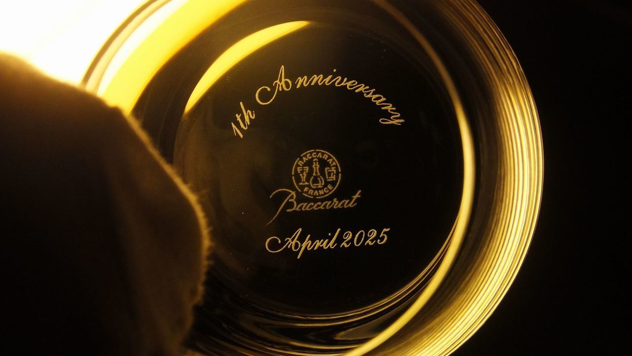 バカラのシャトーバカラ タンブラー Lサイズのクリスタルグラスの底面（フット）を捉えた周年祝いギフトのクローズアップ写真。底面中央には、『1st Anniversary April 2025』という1周年記念のメッセージと日付が繊細に名入れ彫刻されているのが鮮明に確認できる。エレガントなフォルムを持つグラスの底面に施された洗練された刻印が、大切な節目の始まりと未来への期待を象徴し、特別な記念品としての格調高い輝きを放つ。