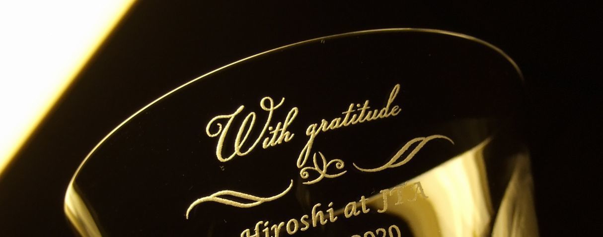 バカラグラスの側面に、『with gratitude』と、その下に装飾デザインを施した名入れ彫刻の写真。透明なクリスタルに、感謝のメッセージとエレガントなデザインが丁寧に刻まれ、心からの感謝を伝える特別なギフトとしての価値と、洗練された美しさを際立たせています。