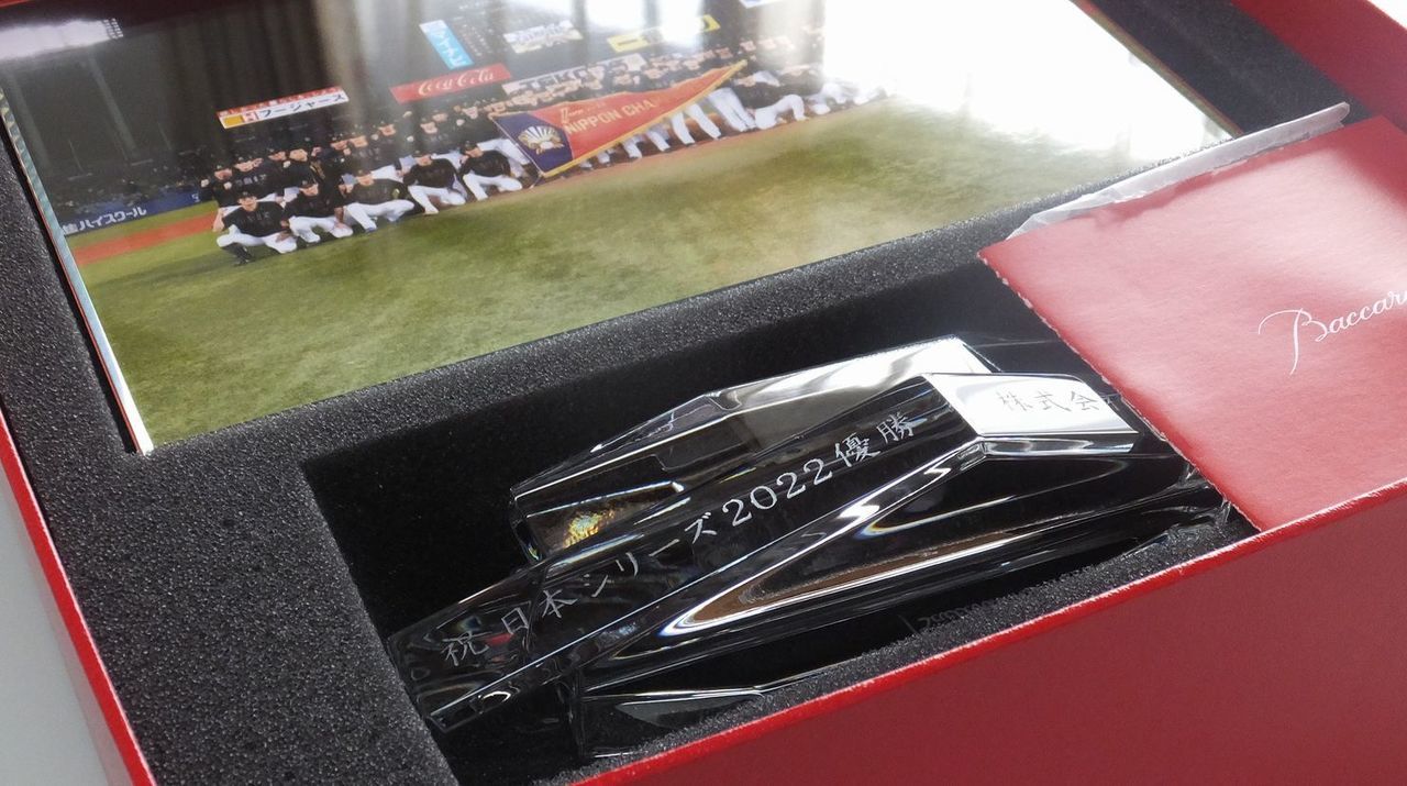 バカラのクリスタル製フォトフレーム『アビス』の重厚な台座部分に、プロ野球日本シリーズ優勝を祝した名入れ彫刻を施したサンプル画像。直線的でエッジの効いた台座に、『祝 日本シリーズ2022優勝』の文字と『贈り主名』が、頂点を極めた覇者にふさわしい力強く格調高い書体で精緻に刻印されている。深海（アビス）をイメージした大胆なカットが光を多方向に反射し、日本一という最高の栄誉とその輝きを象徴しており、歓喜の瞬間を収めるための、威厳と品格に満ちた最高峰のアニバーサリーギフトであることを視覚的に表現している。