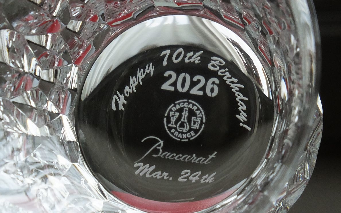 バカラ（Baccarat）の『ダリア タンブラー 2026』の底面に、英語で『Happy 70th Birthday』のメッセージと『Mar.24th』の日付が精緻に名入れ彫刻された写真。最高級クリスタルならではの透き通る輝きと年号刻印に、古希（70歳）という人生の節目を祝福する特別な彫刻が映え、70歳の誕生日祝いや長寿のお祝いに贈る最高峰のパーソナルギフトのイメージ。