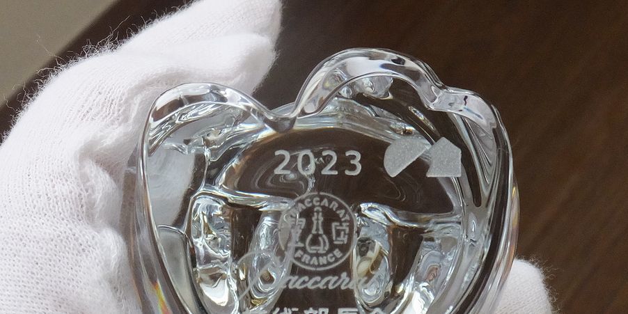 バカラの招き猫 クリアの底面に、『2023』と積水ハウスのロゴを名入れ彫刻した写真。透明なクリスタル製の愛らしい招き猫の底に、記念すべき年と企業のロゴが繊細に刻まれています。幸運を招く縁起の良いアイテムとして、企業ノベルティや特別な記念品にふさわしい逸品です。