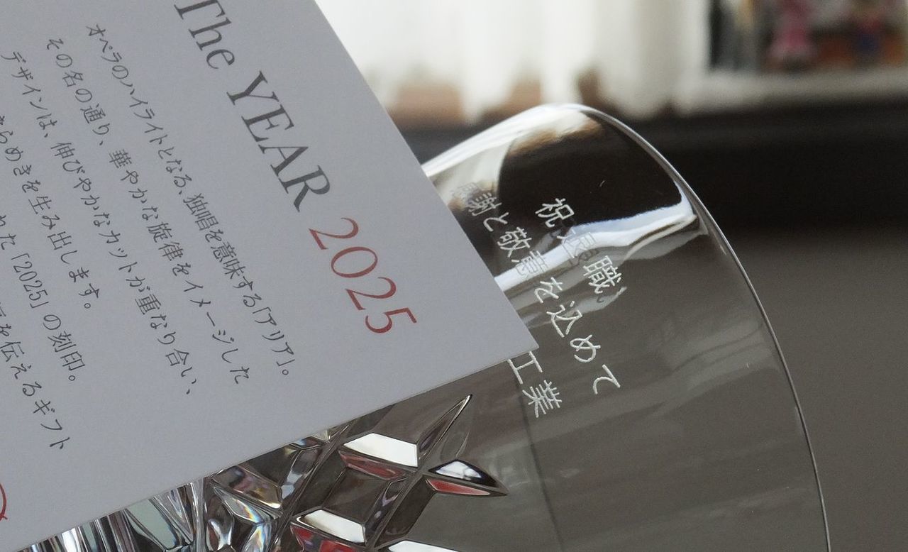 バカラの『アリア タンブラー 2025（イヤータンブラー）』の側面に名入れ彫刻を施した退職祝い記念品の制作実績。空気が振動するさまをイメージしたデザインのタンブラーの側面に、『祝 退職 感謝と敬意を込めて [企業名]』のメッセージが和文書体（行書体または明朝体）で精巧に刻印されている。年号入りの限定品に、長年の功績を称える温かいメッセージを刻むことで、深い感謝と格式を伝える特別な記念ギフトとして視覚的に伝えている。