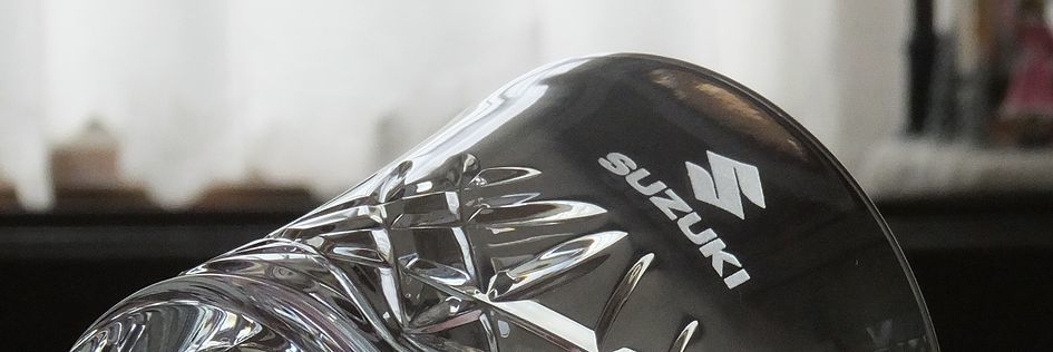 バカラのアリアタンブラー2025の側面に、自動車メーカーのスズキのロゴを名入れ彫刻した写真。透明なクリスタルに、スズキのロゴが繊細に刻まれており、企業の周年記念や社員表彰など、特別な記念品としての価値と、洗練されたデザインを際立たせています。