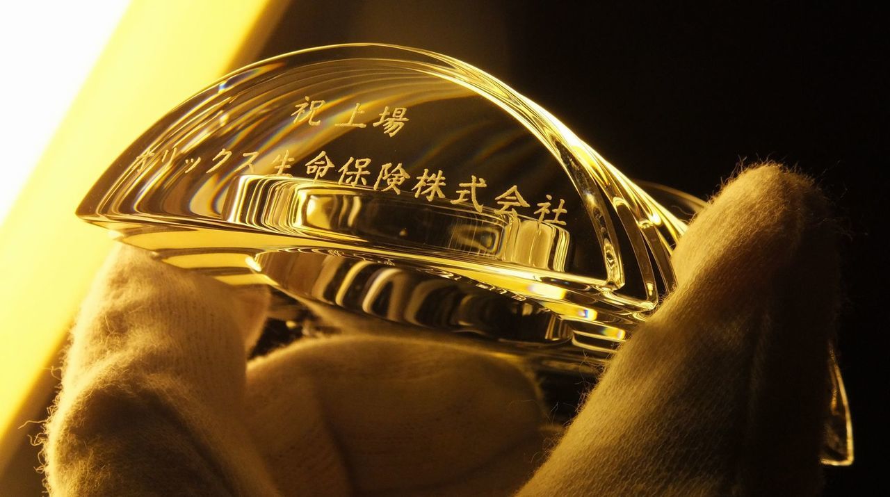 バカラのクリスタル製置き時計『ラランドクロック』に、上場記念の特注彫刻を施したサンプル画像。円形クリスタルの上部カーブに沿って、『祝上場 オリックス生命保険株式会社』の文字が、信頼と誠実さを感じさせる端正な楷書体で精巧に刻印されている。天文学者の名を冠したこの時計の透明な輝きが、企業の新たなステージへの躍進と、お客様と共に刻んでいく確かな未来の時間を象徴しており、上場という栄えある節目を祝う最高峰の記念ギフトであることを視覚的に表現している。