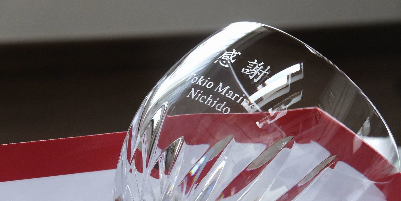 バカラ（Baccarat）の『マッセナ』ワイングラスの側面に、漢字の『感謝』と『Tokio Marine Nichido』の文字が精緻に名入れ彫刻された写真。丸みを帯びた重厚感あるフォルムと深いカットワークが特徴の最高級クリスタルガラスに、感謝の意を込めた文字と東京海上日動の英字ロゴが美しく映え、創立記念、退職祝い、あるいは特別な取引先への贈答品にふさわしい、気品と信頼感にあふれた格調高いイメージ。