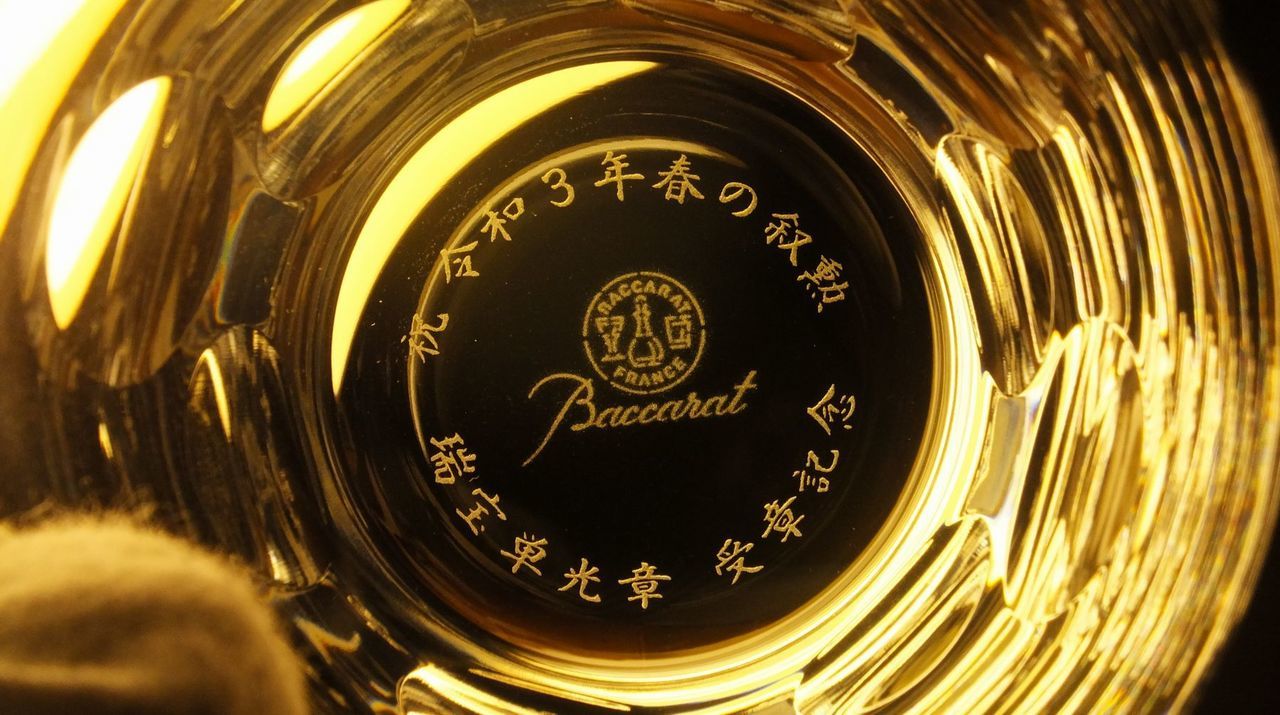 バカラ（Baccarat）のクリスタルタンブラー『ベルーガ』の底面に、漢字で『祝 令和3年春の叙勲 瑞宝単光章 受章記念』の文字が精緻に名入れ彫刻された写真。丸いドット状のカットが可憐で美しい光の反射を生み出す最高級クリスタルに、長年の公的な功績や社会への深い貢献と栄誉ある受章を祝福する刻印が施され、叙勲・褒章のお祝いや記念品にふさわしい最高峰の格調高いギフトのイメージ。
