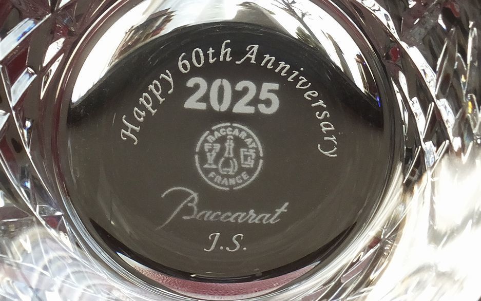 バカラ（Baccarat）の『アリア タンブラー 2025』の底面に、英語で『Happy 60th Anniversary』のメッセージとイニシャル『J.S』が精緻に名入れ彫刻された写真。最高級クリスタルならではの透き通る輝きと年号刻印に、ダイヤモンド婚式（結婚60周年）や還暦、還暦創業などの大きな節目を祝福する特別な刻印が映え、60周年の記念日祝いや長寿のお祝いに贈る最高峰のギフトのイメージ。