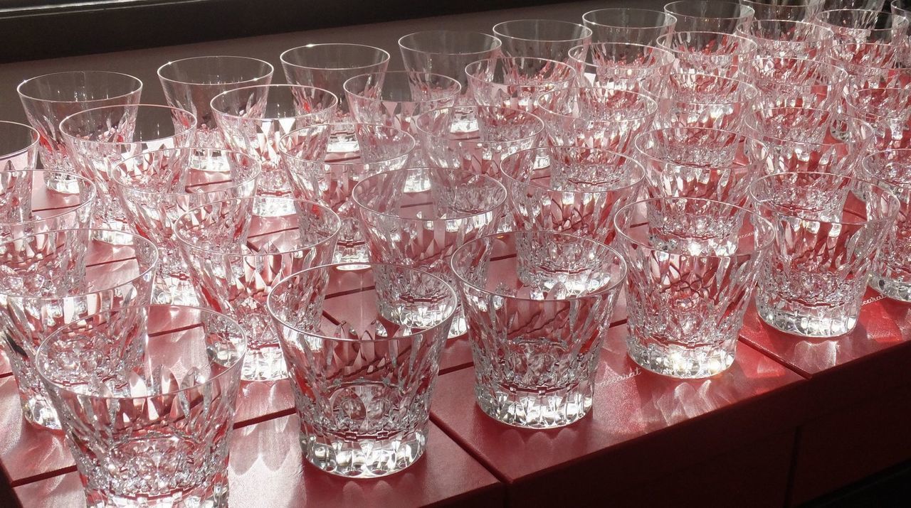 バカラの象徴的なレッドボックスの上に、名入れ彫刻を施したダリア タンブラー 2026がいくつも並べられた写真。鮮やかな赤いギフトボックスと、その上に整然と並ぶクリスタルグラスの輝きが、大規模な記念行事や式典の華やかな贈呈シーンを演出するイメージ。