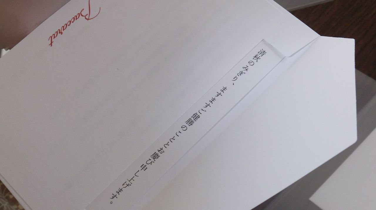 法人向けの周年記念品として、バカラのメッセージカードが名入れ彫刻を施したクリスタルグラスの傍らに美しく添えられている写真。バカラのブランドロゴが記された上品で厚みのあるカードには、『創立周年のお祝いと日頃の感謝』を伝えるメッセージが丁寧に記されている。背景には、バカラの象徴であるレッドボックス**と、光を反射して輝く記念グラスが配置されており、単なる贈り物以上の、敬意と真心を込めた特別な法人ギフトであることを視覚的に表現している。