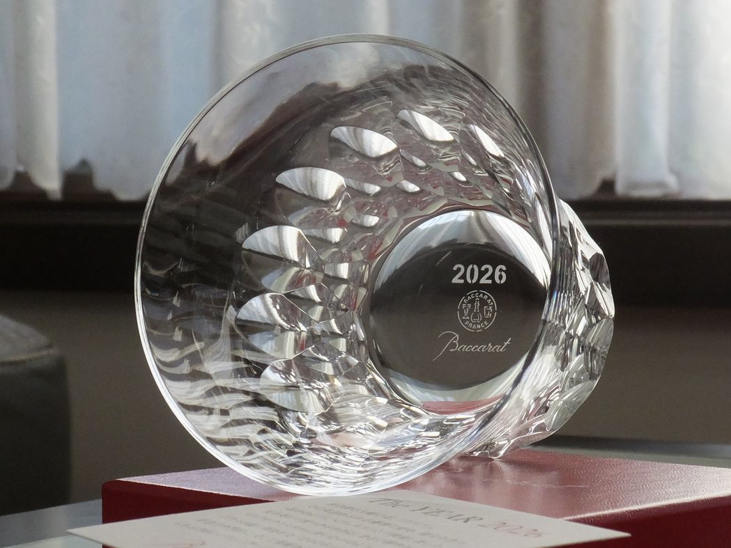 バカラの象徴的なレッドボックスの上に置かれた、2026年の年号を冠したイヤータンブラー『ダリア』の写真。クリスタルの透明感と赤いギフトボックスのコントラストが美しく、特別な記念日の贈り物としての品格を伝えるイメージ。