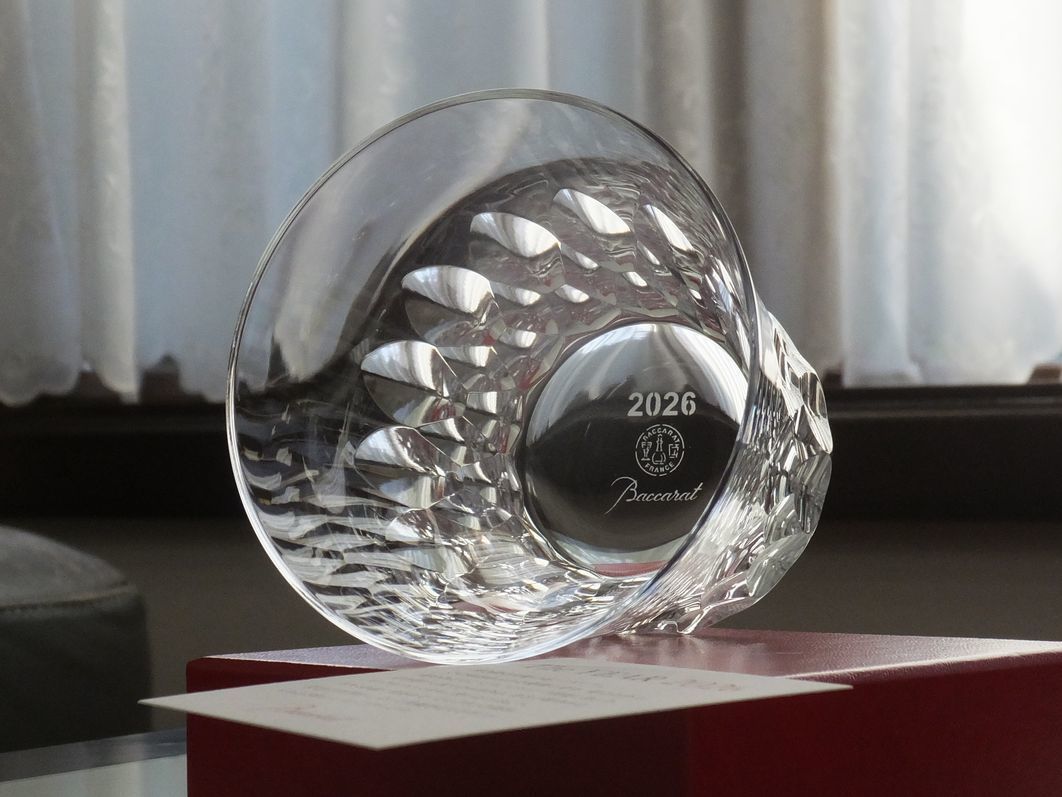 バカラのアリアタンブラー2025が、レッドボックスの上に置いてある写真。透明なクリスタル製のタンブラーが、バカラの象徴的な赤い箱の上に置かれ、その透明感と赤色のコントラストが、贈り物としての高級感と特別感を際立たせています。